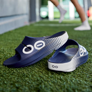 OOFOS recovery sandals being rinsed after a muddy trail run