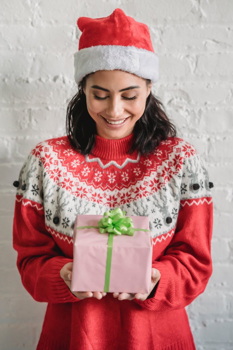 woman in a christmas jumper holding a xmas gift