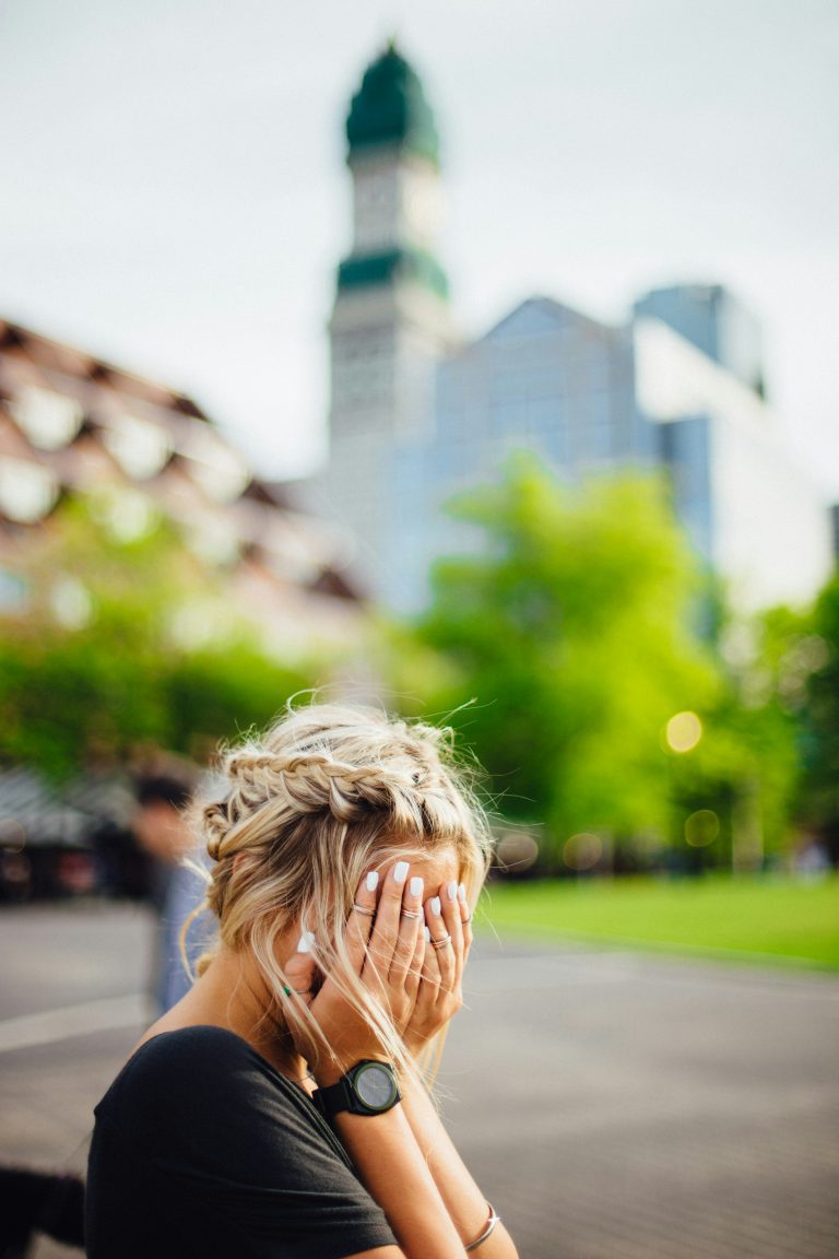 woman with head in hands outdoors