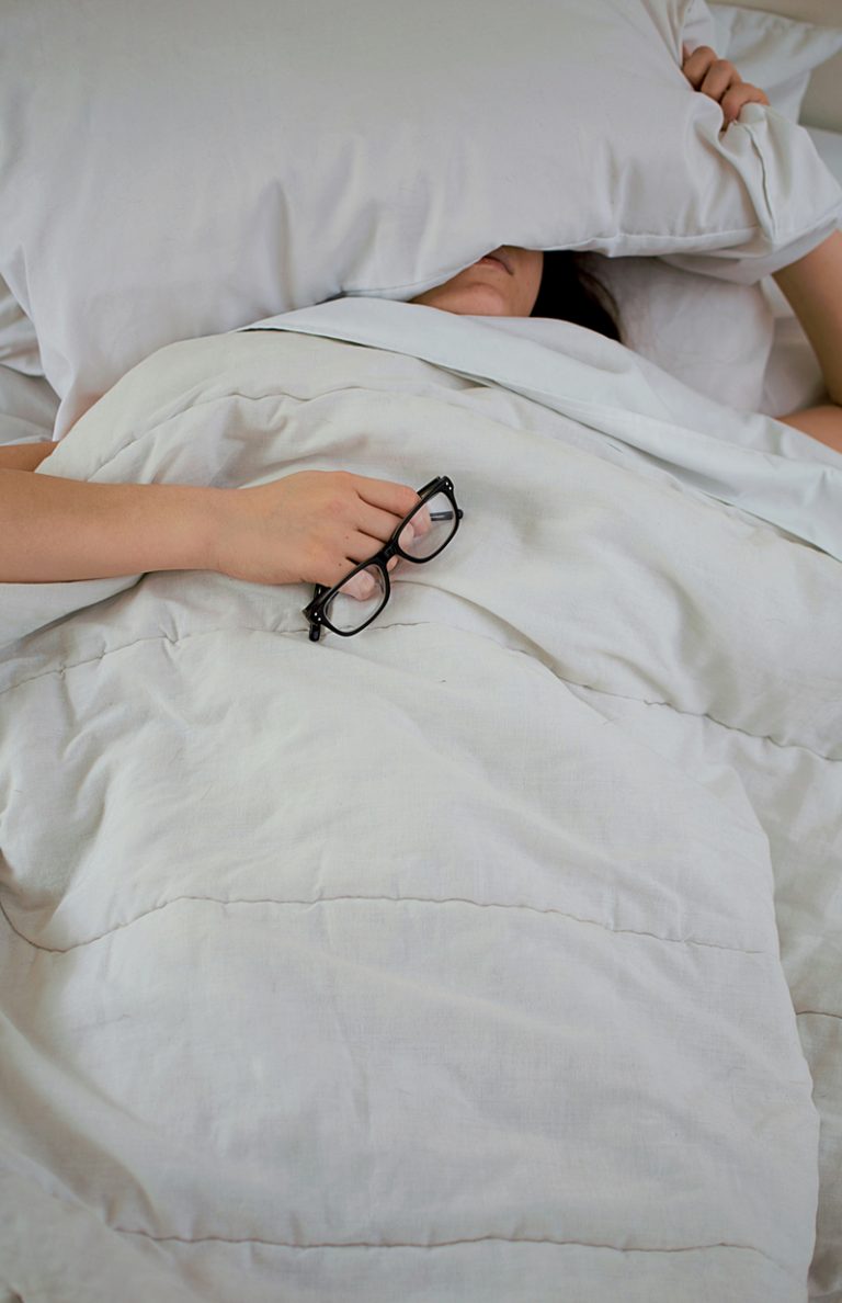 person in bed holding a pair of glasses
